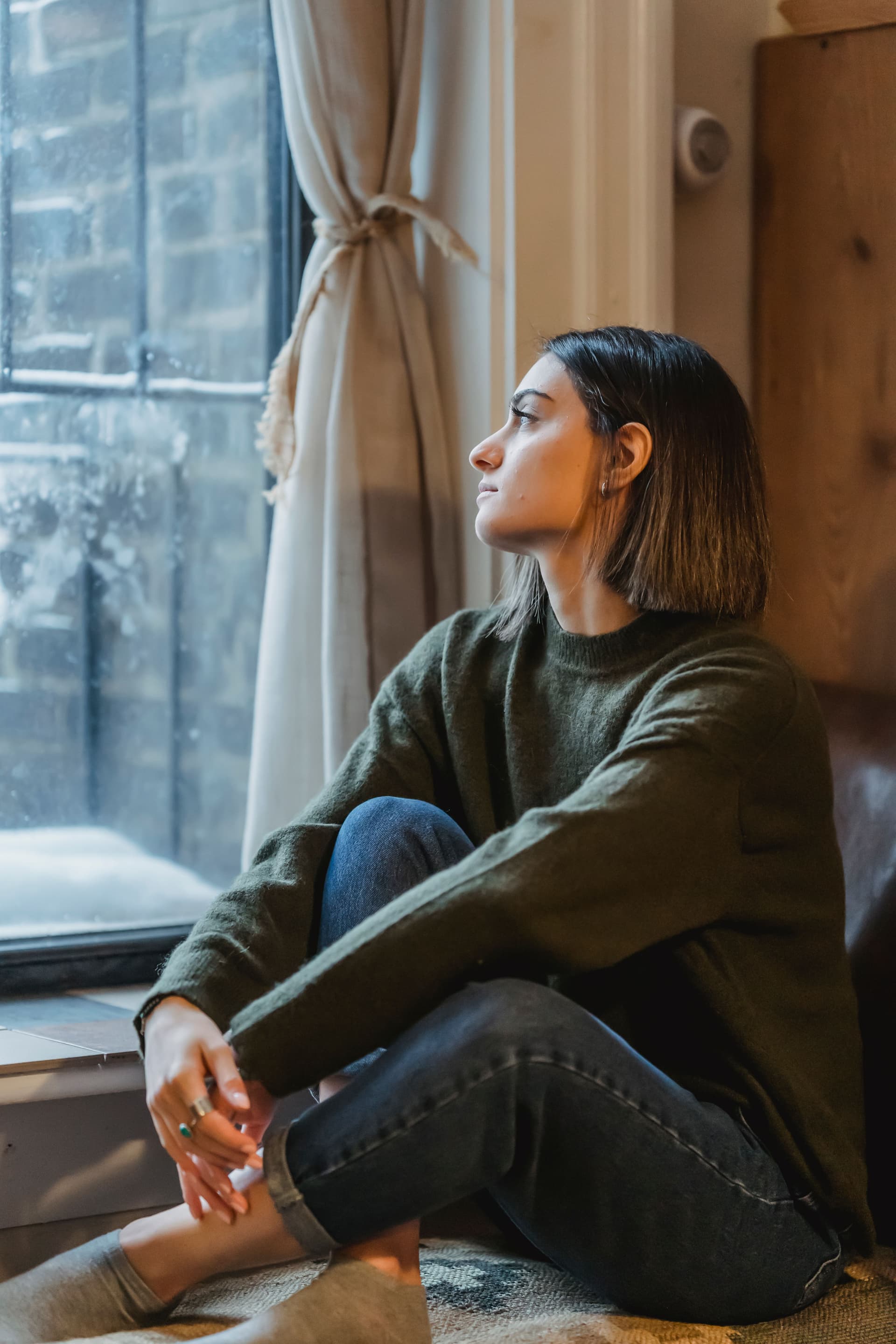 Woman sitting by a window in quiet reflection